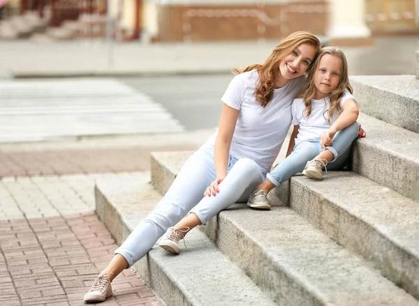 Beautiful woman and her little daughter sitting on stairs outdoors — Stock Photo, Image