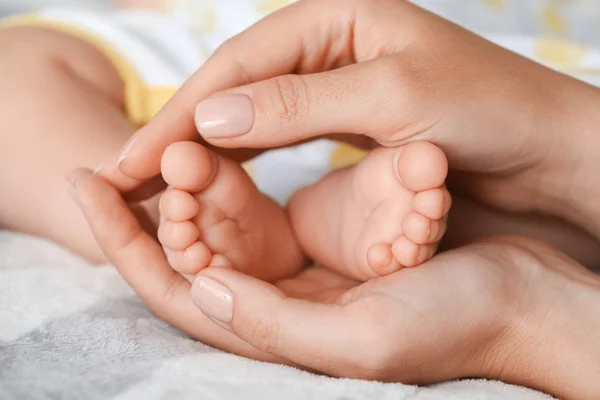 Mother touching feet of her cute little baby, closeup — Stock Photo, Image