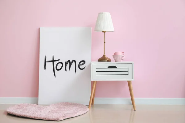 Modern table with lamp and picture near color wall — Stock Photo, Image