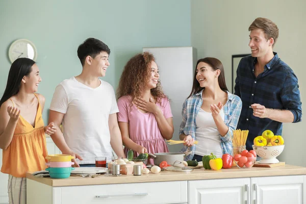 Happy friends cooking together in kitchen — Stock Photo, Image