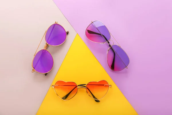 Different stylish sunglasses on color background — Stock Photo, Image