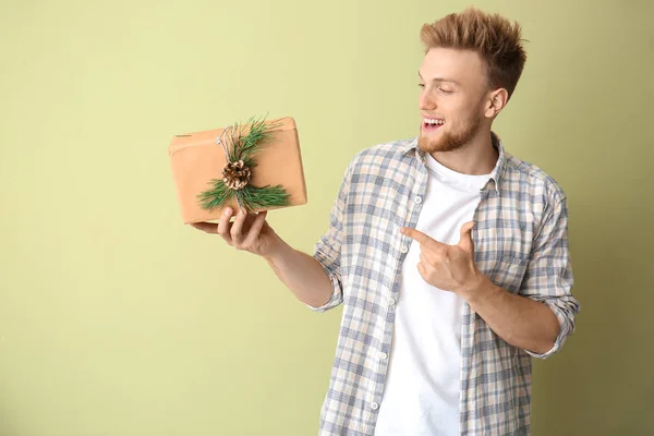 Щасливий молодий чоловік з подарунковою коробкою на кольоровому фоні — стокове фото