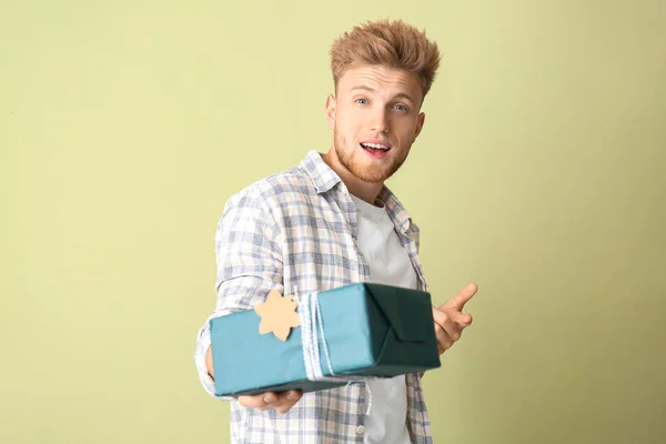 Happy young man with gift box on color background — Stock Photo, Image