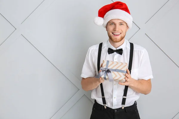 Young man with Christmas gift box on light background — Stock Photo, Image