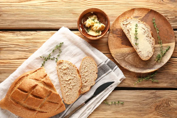 Fresh bread with butter and herbs on wooden table — Stock Photo, Image