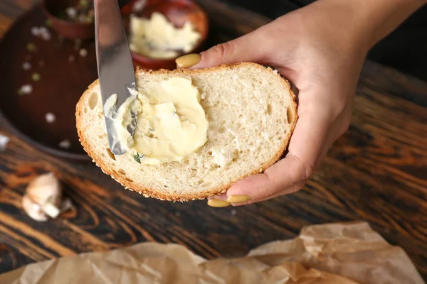 Vrouw verspreidt boter op een stukje vers brood, close-up — Stockfoto