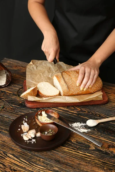 Vrouw snijden vers brood aan tafel, close-up — Stockfoto