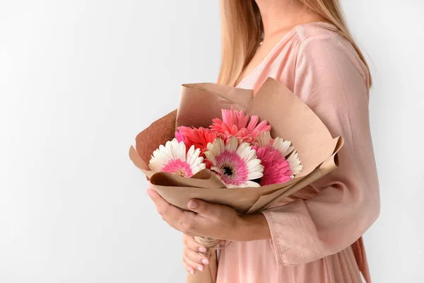 Woman with bouquet of beautiful gerbera flowers on light background — Stock Photo, Image