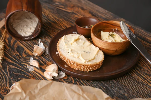 Stukje vers brood met boter, specerijen en knoflook op houten tafel — Stockfoto