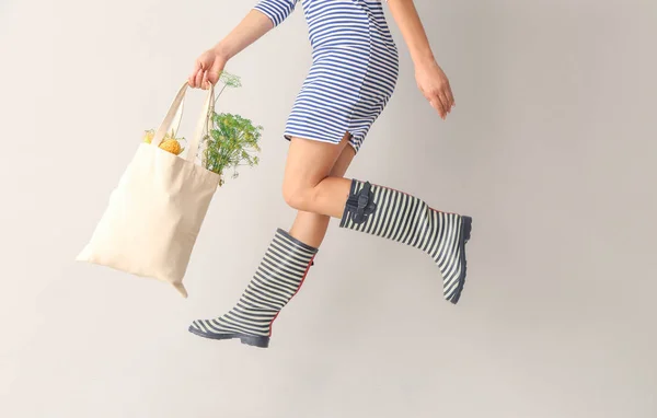 Mujer saltando con bolsa ecológica sobre fondo claro —  Fotos de Stock