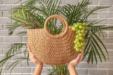 Gri tuğla duvara yakın eko çanta ile Kadın eller