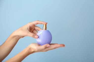 Renkli arka planda parfüm şişesi ile kadın elleri