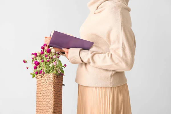 Mujer con libro y flores en bolso ecológico sobre fondo claro —  Fotos de Stock