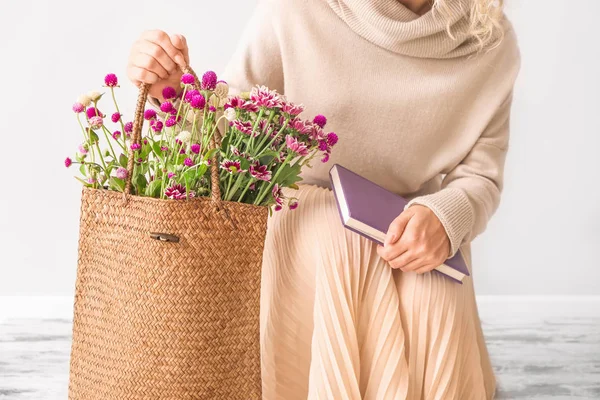 Femme assise avec livre et fleurs dans un sac écologique à l'intérieur — Photo