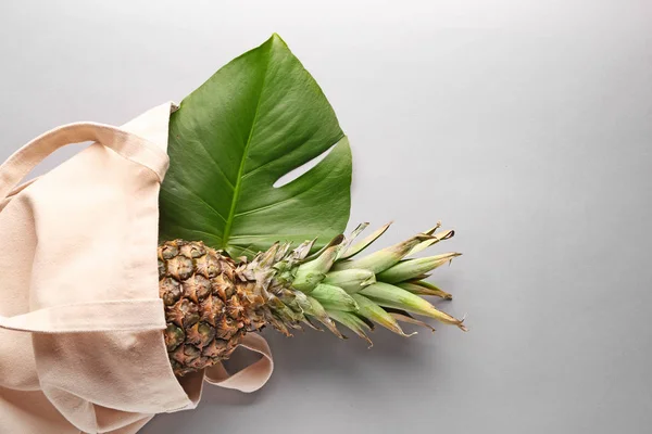 Öko-Tasche mit Ananas und tropischem Blatt auf grauem Hintergrund — Stockfoto