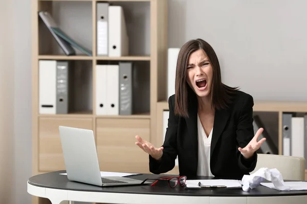 Стрессовая молодая женщина на рабочем месте в офисе — стоковое фото