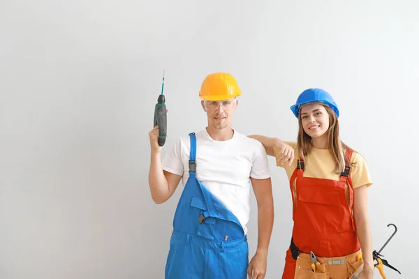 Happy young couple with tools on light background — Stock Photo, Image