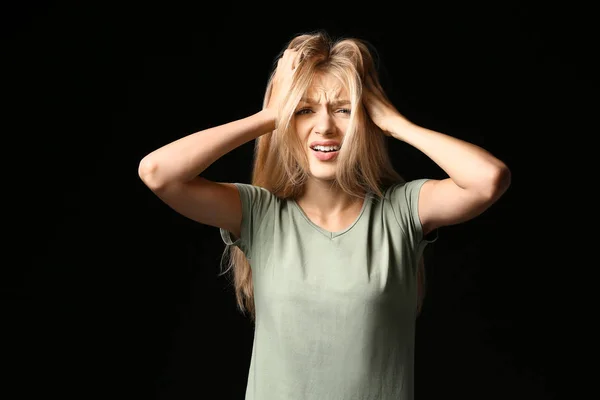 Gestresste junge Frau auf dunklem Hintergrund — Stockfoto