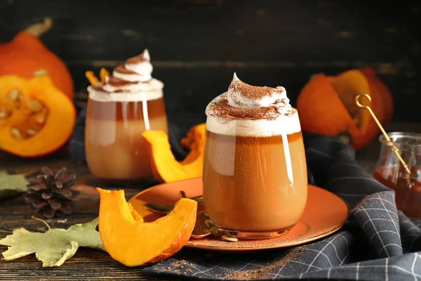 Glass of tasty pumpkin coffee on table