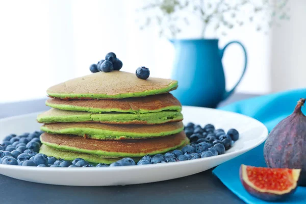 Plate med velsmakende grønne pannekaker og bær på bordet – stockfoto