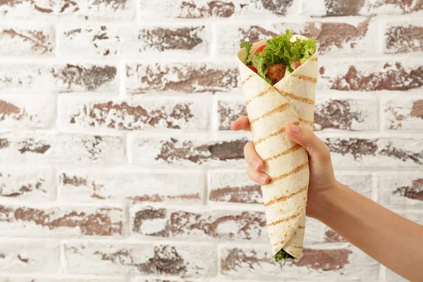 Female hand with tasty falafel pita against brick wall — Stock Photo, Image