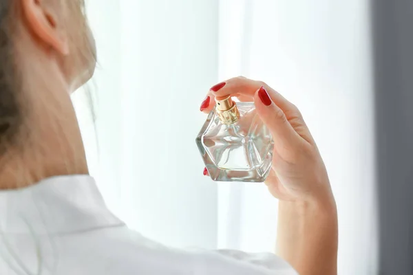 Femme avec bouteille de parfum à la maison — Photo