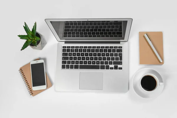 Moderner Laptop, Mobiltelefon, Notebooks und Tasse Kaffee auf weißem Hintergrund — Stockfoto