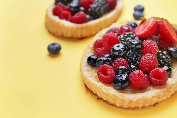 Süßes Törtchen mit Beeren auf farbigem Hintergrund — Stockfoto