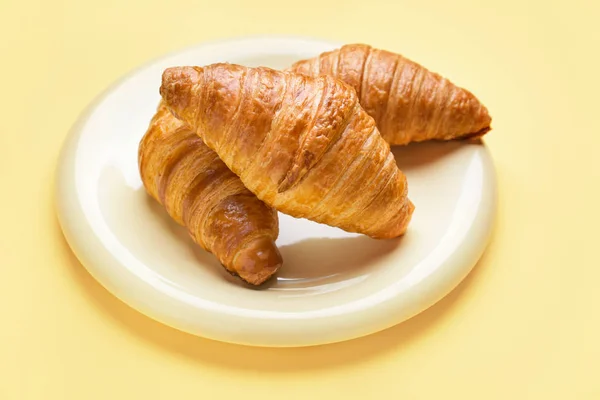 Piatto con dolci croissant su sfondo colore — Foto Stock