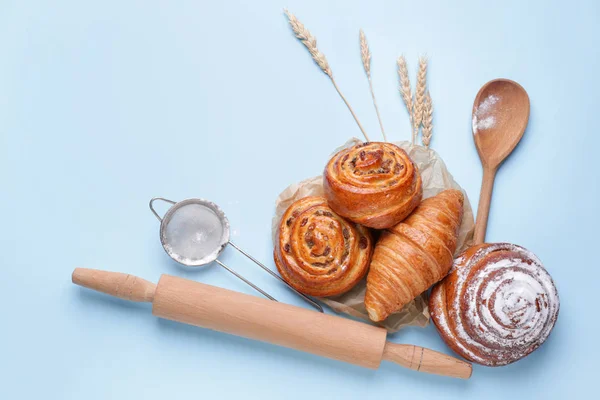 Sweet pastry with utensils on color background