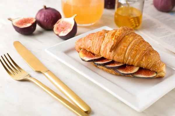 Prato com croissant doce e fatias de frutas de figo na mesa — Fotografia de Stock