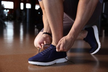Spor salonunda ayakkabı bağcıkları bağlama sportif genç adam