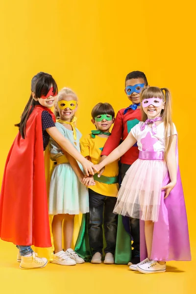 Bonito crianças vestidas como super-heróis em fundo de cor — Fotografia de Stock