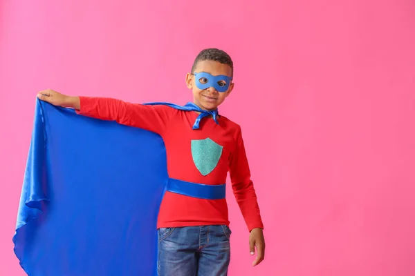 Cute African-American boy dressed as superhero on color background — Stock Photo, Image