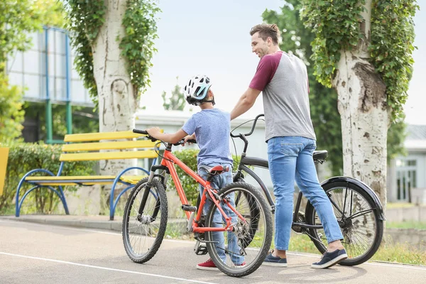 Feliz padre e hijo montando bicicletas al aire libre — Foto de Stock