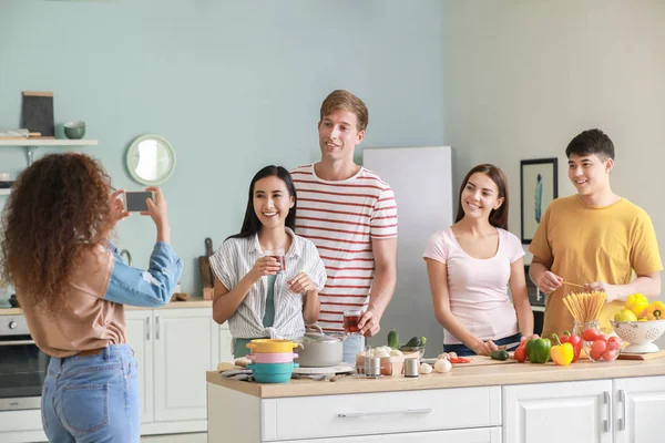 African-American woman taking photo of her friends cooking in kitchen — Stock Photo, Image