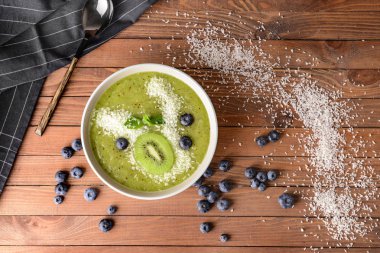 Ahşap masada lezzetli kivi smoothie ve yaban mersini ile Bowl