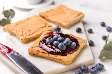Beyaz tahta üzerinde tatlı reçel ve fıstık ezmesi ile tost ekmeği