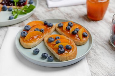 Beyaz masada tost ekmeği, kayısı reçeli ve yaban mersini ile tabak
