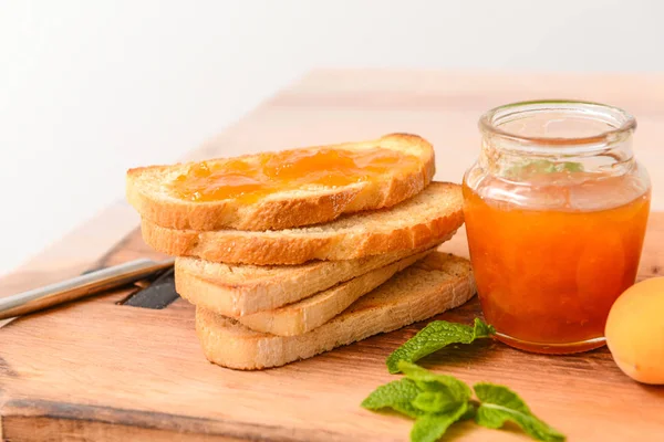 Toasted bread with apricot jam on wooden board — Stock Photo, Image