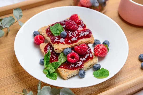 Plate with toasted bread, tasty jam and berries on tray, closeup — Stock Photo, Image