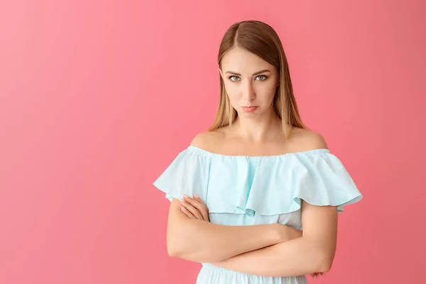 Offended young woman on color background
