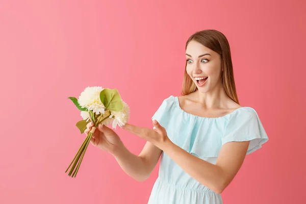 Surprised young woman with bouquet of flowers on color background — Stock Photo, Image