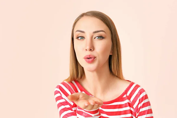 Beautiful young woman blowing kiss on color background — Stock Photo, Image