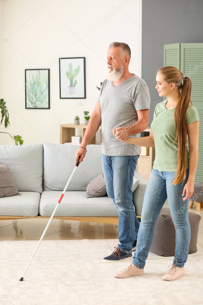 Woman helping blind mature man at home