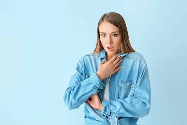 Shocked young woman on color background — Stock Photo, Image