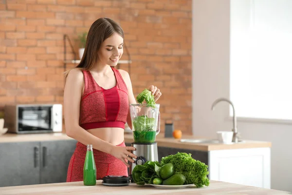 Jonge sportieve vrouw bereidt gezond groentesap in de keuken — Stockfoto
