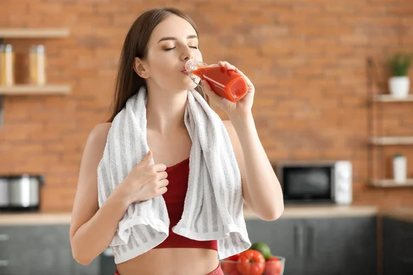 Young sporty woman drinking healthy vegetable juice in kitchen — Stock Photo, Image