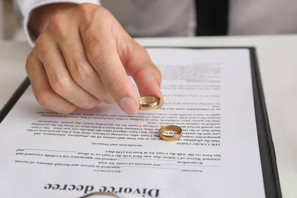 弁護士事務所のテーブルに座って離婚令と指輪を持つ男、クローズアップ — ストック写真