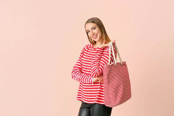 Mooie jonge vrouw met tas op kleur achtergrond — Stockfoto